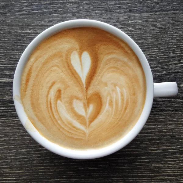 Bir fincan kahve latte sanat üstten görünüm ahşap arka plan üzerinde.