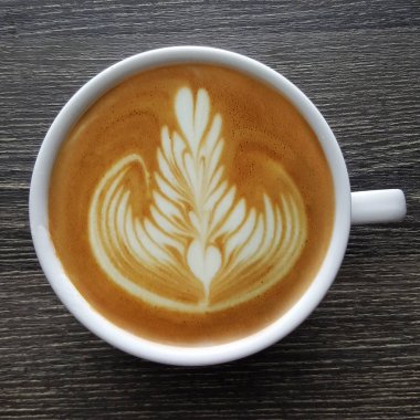Bir fincan kahve latte sanat üstten görünüm ahşap arka plan üzerinde.