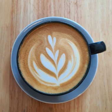 Bir fincan kahve latte sanat üstten görünüm ahşap arka plan üzerinde.