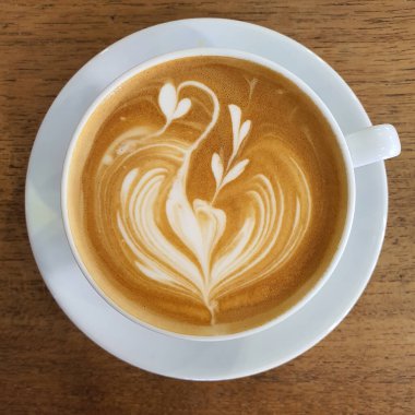 Bir fincan kahve latte sanat üstten görünüm ahşap arka plan üzerinde.