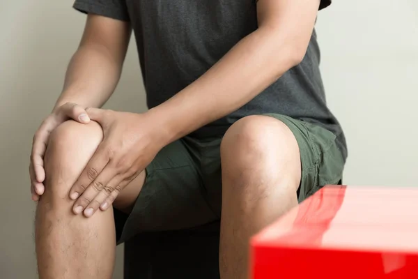 The knee man holds on suffering from pain in knee Closeup. The lesion is highlighted in red. — Stock Photo, Image