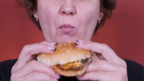 Een vrouw die een hamburger eet. Een close-up schot. Fast food eet. Burger in vrouwelijke handen. — Stockvideo