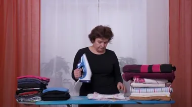 Evde ev işi yaparken dans eden bir kadın. Eğlenceli ev hanımı ütü yapıyor. 