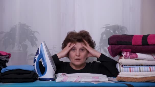 Депрессивная, уставшая домохозяйка гладит одежду — стоковое видео