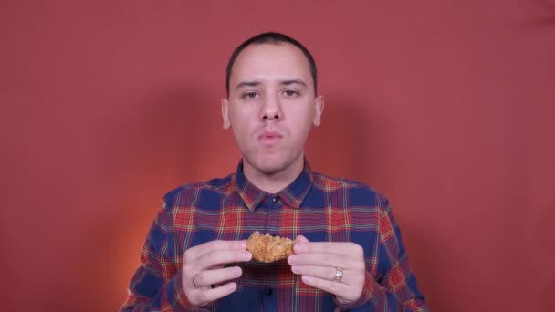 Jím výborné smažené kuřecí křidýlko. Mladý muž jí kuřecí křidýlka. — Stock video