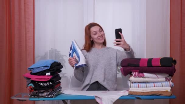 Junge Frau macht ein Selfie beim Bügeln. — Stockvideo
