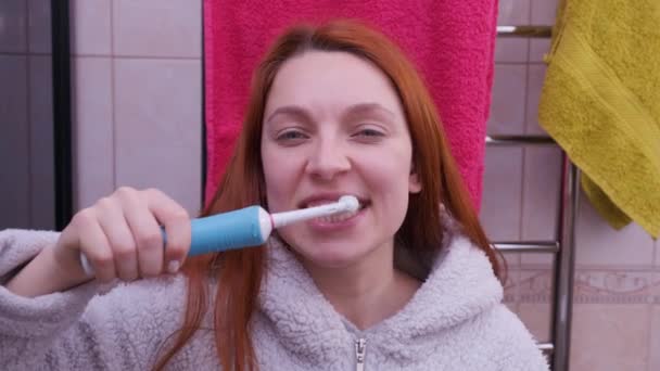 Donna in bagno spazzolatura denti con spazzolino da denti elettrico — Video Stock