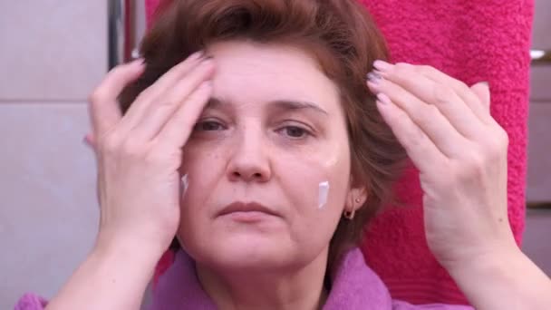 Mujer en baño aplicando crema facial. De cerca. — Vídeos de Stock