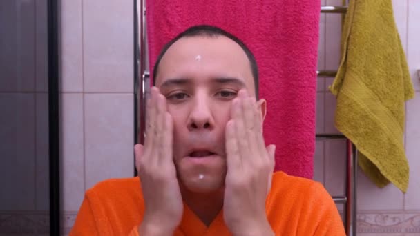 Мужчина наносит крем для лица — стоковое видео