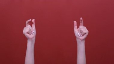 Kadın eli parmaklarını şaklatarak müzik ritmi oluşturur. Stüdyonun kırmızı arka planında izole bir şekilde.