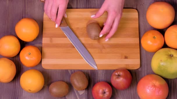 Mãos femininas cortando kiwi fresco na cozinha — Vídeo de Stock