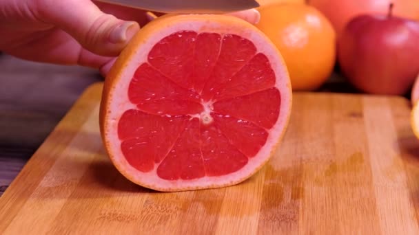 Fecha. Mãos de mulheres que cortam toranja fresca na cozinha — Vídeo de Stock