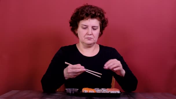 Kvinna vet inte hur man använder kinesiska ätpinnar. — Stockvideo