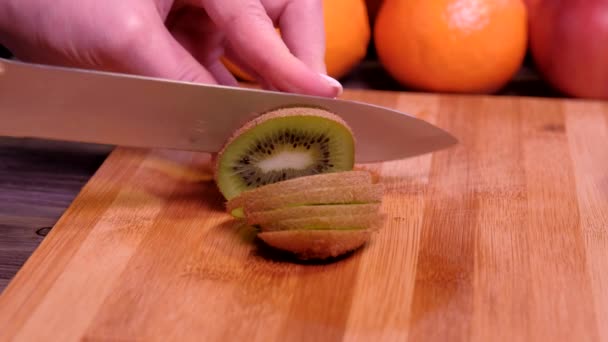 Mãos femininas cortando kiwi fresco na cozinha — Vídeo de Stock
