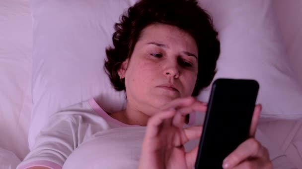 Ovanifrån vuxen kvinna vakna upp och använda sin smartphone — Stockvideo