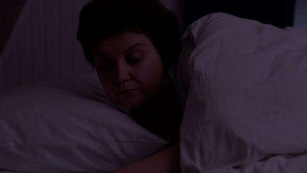 Νυχτερινός συναγερμός. Ενήλικες γυναίκα ξυπνάει τη νύχτα Από το ξυπνητήρι στο τηλέφωνο — Αρχείο Βίντεο