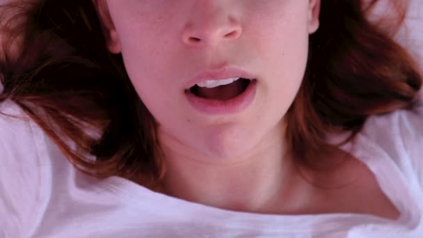 Close up jonge vrouw geeuwt in bed in de ochtend. — Stockvideo
