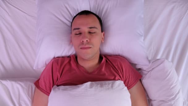 Молодой человек спит на белой подушке . — стоковое видео