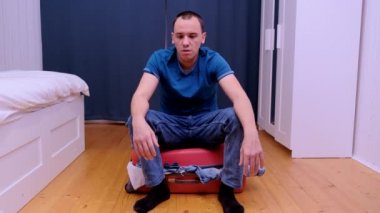 The man was unable to close a travel suitcase filled with clothes