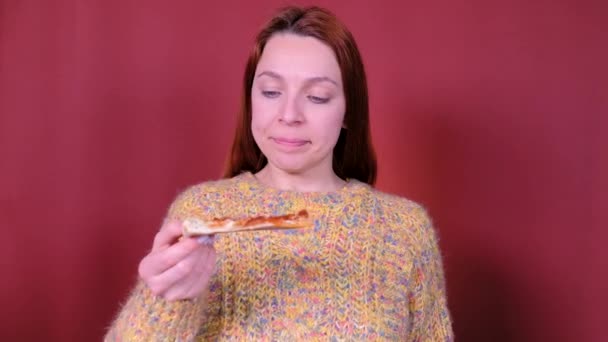 Een vrouw die pizza eet op een rode achtergrond. Fast food eet. — Stockvideo