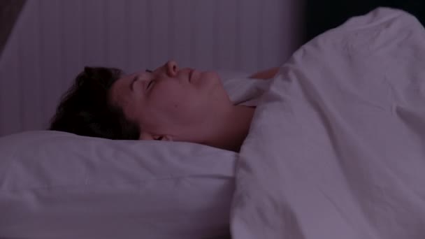 Volwassen vrouw slaapt op een bed en draait zich om 's nachts — Stockvideo