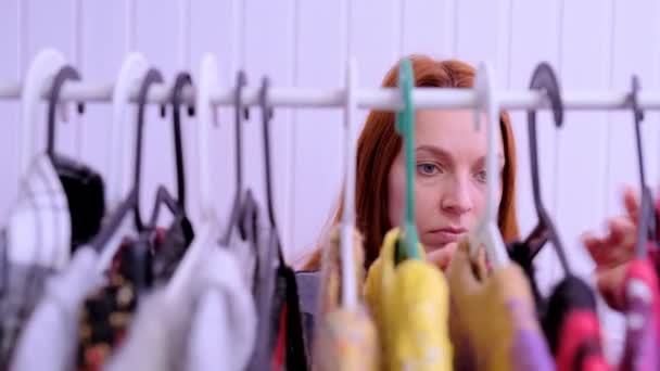 Jonge vrouw kiest jas op rek in showroom — Stockvideo