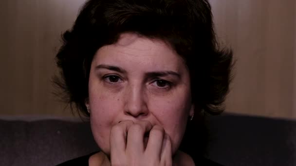 Vyděšená žena sedí na pohovce v noci snaží sledovat strašidelný film sama. — Stock video