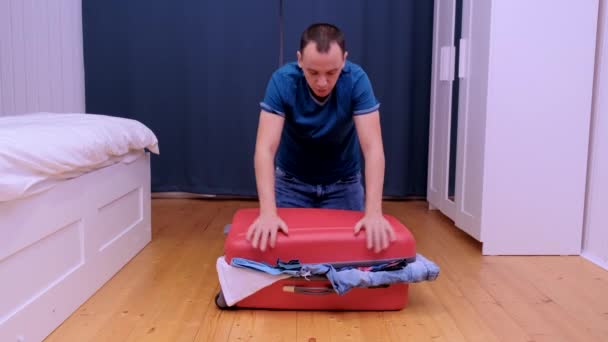 Une jeune femme tente de fermer une valise pour voyager. La valise est pleine de vêtements — Video