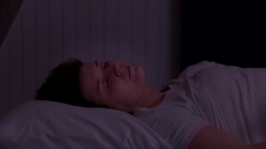 Kadın gürültüden uyuyamıyor ve gece başını yastıkla örtüyor.