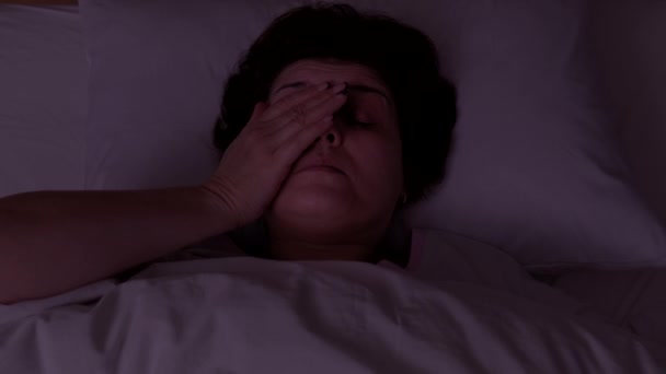 Vista superior. Mulher adulta está dormindo em um travesseiro branco. She está acordando na noite — Vídeo de Stock