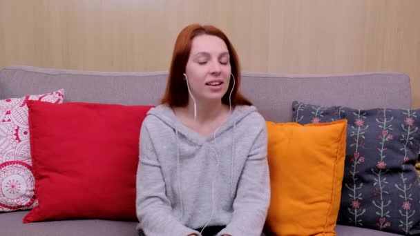 Calm happy young woman in headphones chilling sitting on sofa — Stock Video