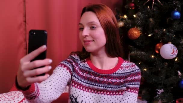 Mujer joven tomando foto selfie cerca del árbol de navidad decorado. concepto de vacaciones y año nuevo . — Vídeos de Stock