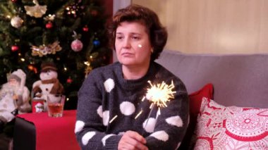 Noel ağacının yanındaki kanepede oturan yalnız bir kadının portresi. Tatil ve yeni yıl konsepti.