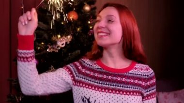 Noel arifesinde Bengal ışıkları olan bir kadın. Noel ağacının arka planında. Tatil, Noel ve Yeni Yıl kavramı.