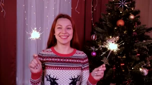 Vrouw met bengaalse lichten op kerstavond. Op de achtergrond van de kerstboom. Begrip vakantie, kerst en nieuwjaar. — Stockvideo