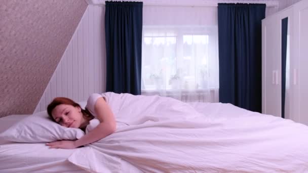 Rothaarige Frau streckt sich und steht aus dem Bett auf. Glückliches junges Mädchen begrüßt neuen Tag — Stockvideo