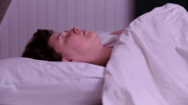Yetişkin bir kadın yatakta yatar ve arkasını döner. — Stok video