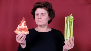 Sağlıklı ya da sağlıksız yemek seçen bir kadın. Diyet kilo kaybı sağlık hizmeti konsepti. Pizza ve Serdula arasında seçim yapan bir kız. Sağlıklı ya da hızlı, abur cubur. Yararlı ya da zararlı bir yaşam tarzı.