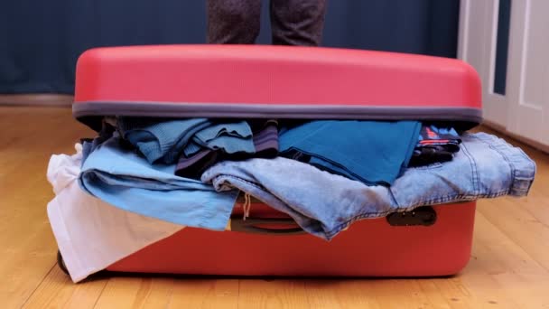 A young woman tries to close a suitcase for travel. — Stock Video