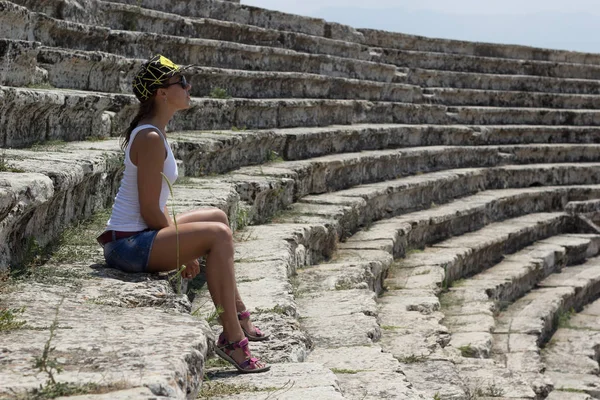 Young beautiful woman sitting in the amphitheater. Pamukkale, Turkey