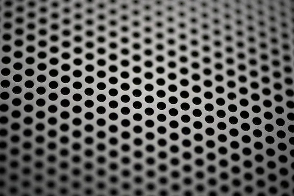 Yuvarlak deliklerin delindiği metalik bir zemin. Yuvarlak delikli siyah metal desenli. Sanayi geçmişi.