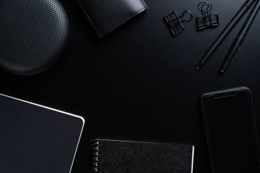 Siyah biçim seti: Siyah arkaplan üzerinde not defteri, kalem ve kağıt ataçları