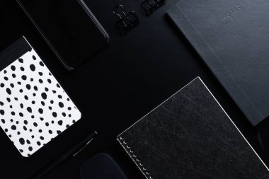 Siyah biçim seti: Siyah arkaplan üzerinde not defteri, kalem ve kağıt ataçları