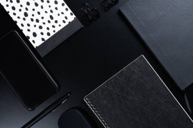 Siyah biçim seti: Siyah arkaplan üzerinde not defteri, kalem ve kağıt ataçları