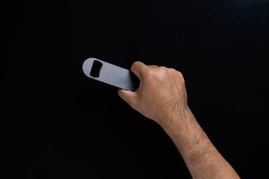 Siyah arka planda izole edilmiş siyah bir şişe açacağını tutan bir adam..