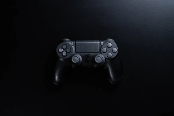 A black game controller isolated on black background.