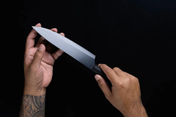 黒の背景に隔離された黒いシェフのナイフを持っている男の手 — ストック写真