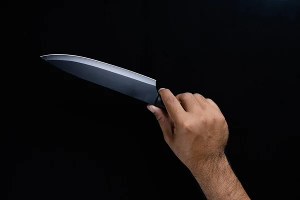 Siyah arka planda siyah şef bıçağını tutan bir adam..
