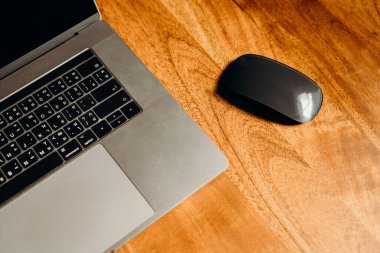 Karanlık bölgedeki ahşap masada bir dizüstü bilgisayar. Üst görünüm.