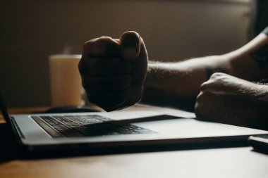 Adamın karanlık bölgede dizüstü bilgisayara vuruşunu yakından çek. Kahveyle fazla mesai yapıyorum..